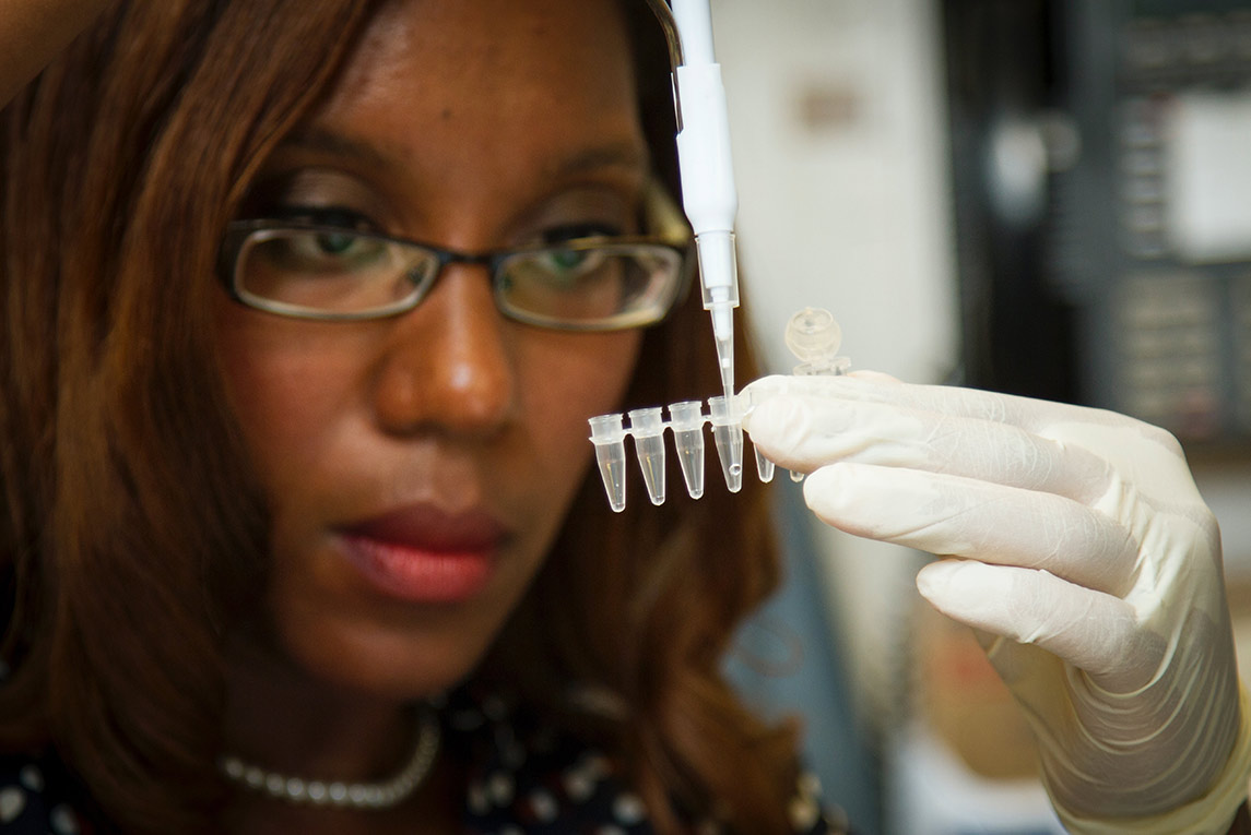 A scientist pipetting DNA samples into a tube.