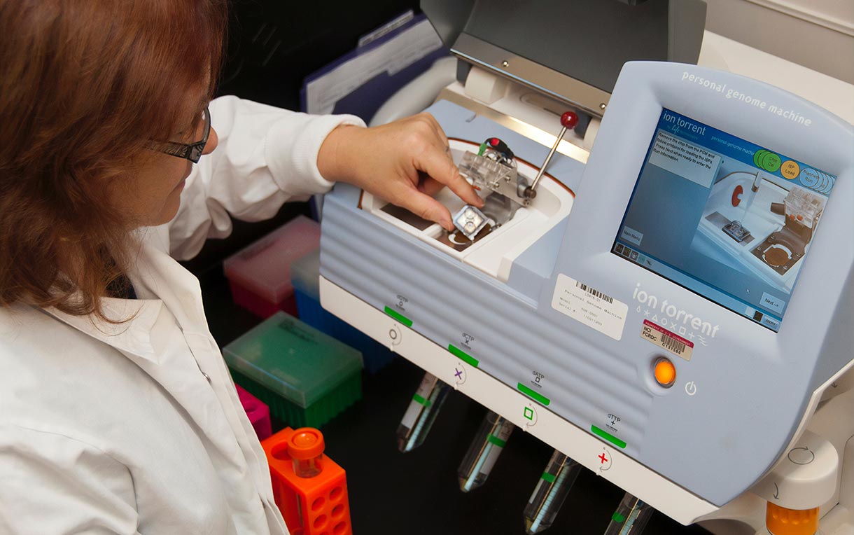 A female lab technician loading a semiconductor DNA sequencing chip.