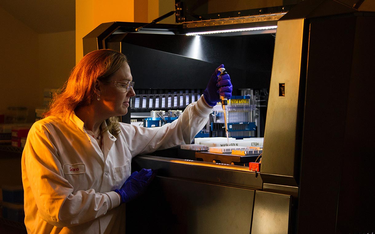 A technician loads robot for DNA genotyping sequencing. 